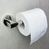 Un rouleau de papier toilette blanc avec un motif en relief ondulé est monté sur un support argenté de la trousse de toilette Xavo Chrome de yessential.fr, fixé sur un mur carrelé gris clair.