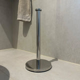L'ensemble de toilette Tygo Chrome (sans perçage) de yessential.fr se tient debout sur le sol carrelé de la salle de bain, sans rouleau de papier toilette. Une serviette beige est finie sur le mur et complète le look moderne.