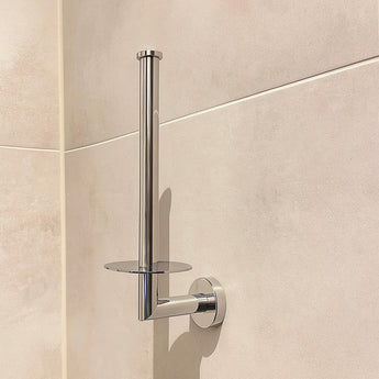 Le porte-rouleau de papier toilette Roberto Chrome de yessential.fr est monté au mur dans une salle de bain carrelée beige, présenté sans papier toilette.