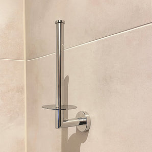 Le porte-rouleau de papier toilette Roberto Chrome de yessential.fr est monté au mur dans une salle de bain carrelée beige, présenté sans papier toilette.