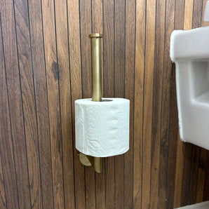 Le porte-rouleau de papier toilette Roberto Gold de yessential.fr, monté verticalement sur un mur en bois à côté d'un lavabo blanc, ajoute une touche stylée et élégante à vos accessoires de salle de bain.