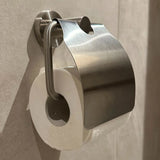 L'ensemble de toilettes Marino en acier inoxydable de yessential.fr comprend un rouleau de papier toilette sur un support mural fin avec un couvercle en métal incurvé brillant - parfait pour ajouter une touche moderne au décor de votre salle de bain.