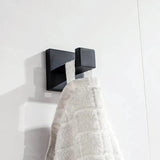 L'ensemble de WC Venzo Black de yessential.fr comprend un élégant crochet mural carré en métal qui maintient une serviette texturée blanche contre des carreaux blancs - un ajout moderne idéal à vos accessoires de salle de bain.