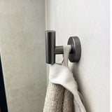 L'ensemble WC Fabiano Gunmetal de yessential.fr est livré avec une serviette blanche et beige au mur - une touche moderne idéale pour le bain.