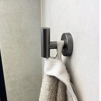 L'ensemble WC Fabiano Gunmetal de yessential.fr est livré avec une serviette blanche et beige au mur - une touche moderne idéale pour le bain.