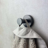 Le grand plan au crochet Kyano Gunmetal de yessential.fr locataire avec une texture serviette beige sur la boucle, montée sur un mur de couleur claire.