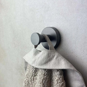 Le grand plan au crochet Kyano Gunmetal de yessential.fr locataire avec une texture serviette beige sur la boucle, montée sur un mur de couleur claire.