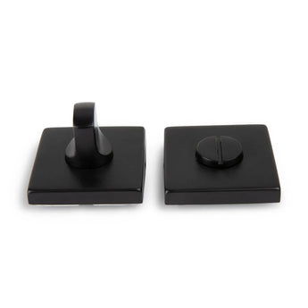 Deux pièces carrées noires de serrure de WC Vano Black de yessential.fr sur fond blanc ; l'un a un petit levier, l'autre une fente pour pièce de monnaie ou tournevis.