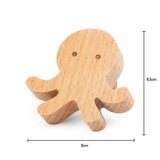La Poulpe Bambino de yessential.fr est une petite figurine en bois aux yeux sculptés simples mesurant 6 cm de large et 6,5 cm de haut. Les coins lisses et arrondis et la finition en bois naturel le rendent parfait pour la chambre de bébé.